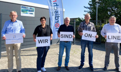 Vertreter des Breitbandzweckverbandes in Mittelangeln posieren mit Schildern vor einem Werbebanner der Marke nordischnet